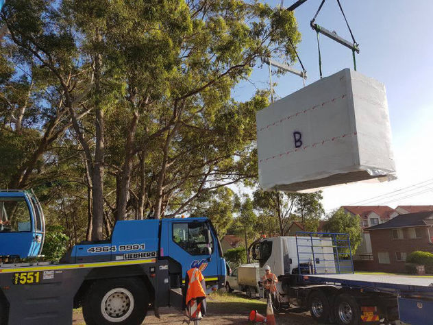 Mobile crane delivers a stack of MAAP hybrid modular panels to the building site