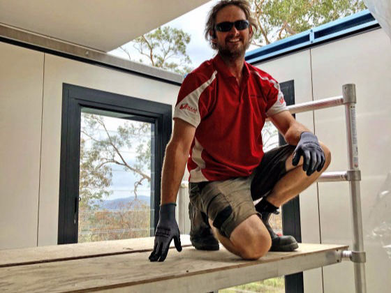 A MAAP Worker pauses while installing hybrid MAAP House ceiling panels