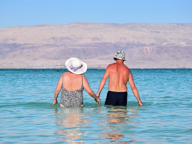 A retired couple walk out into the water to go for a swim